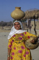 Woman collecting water  carrying one pot on her head and another under her arm.
