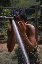 Child in Hmong village washing with water from UNHCR supplied tap.