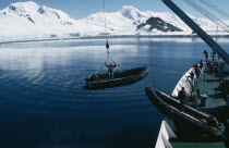 Lowering Zodiacs for taking passengers ashore. Person standing in the small boat whilst being lowered.
