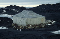 Shackleton s Hut at Cape Royds   with crates stacked around the sides of the weathered wooden building.