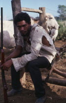 Portrait of a squatter armed with a shotgun  sat down with torn clothing. Brasil