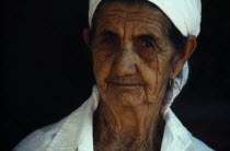 Portrait of an elderly Seringueiro woman with a white shirt and head scarf and gold earrings. Brasil