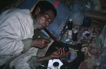 A man laying on the ground smoking opium with a pipe.drugs Burma
