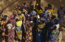 Women pound millet and sing and dance in celebration during traditional funeral ceremony.