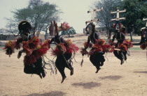 Dogon masked dancers leaping in line.