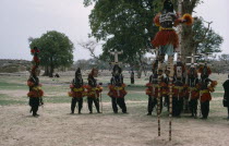 Dogon masked stilt dancer with others on ground below.