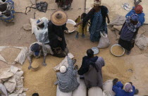 Looking down on traders and customers making transaction at market stall selling grains and pulses.
