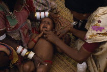 Female health visitor examining tribal baby.