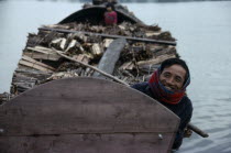 Smiling boatman on barge laden with timber.