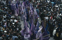 Good Friday procession through the Plaza de San Francisco with hooded penitents dragging crosses through the crowds.