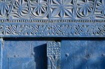 Detail of blue painted doorway with carved plant motif.