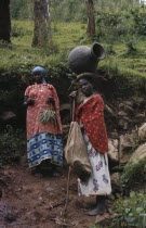 Female agricultural workers with one woman carrying large pot on her head.