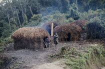 Circular thatched village huts with two children standing outside.