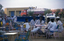 Group of men at outside tables of cafe in evening light.