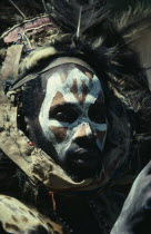 Portrait of Kikuyu man with painted face and wearing fur and feather head dress.