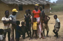 Large family outside thatched building with mud brick walls.