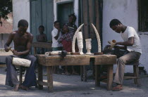 Men carving ivory with watching children. Zaire