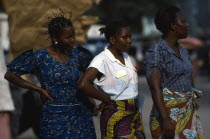 Three women wearing brightly patterned textiles. Zaire