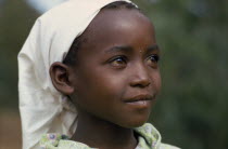 Head and shoulders portrait of young Kikuyu girl wearing headscarf  three quarter profile right.