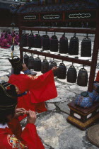 Confucian Rites Ceremony at Chong Shrine. Men in red robes sat on ground sounding chimes  Myo  shrine Chimes  bells