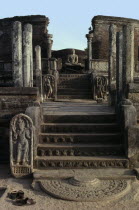 Vatadage circular relic house.  Moonstone or carved stone doorstep at the northern entrance with seated Buddha figure beyond.