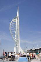 The Spinnaker Tower the tallest public viewing platforn in the UK at 170 metres on Gunwharf Quay with tourists on the deck of a harbour tour boat in the foreground