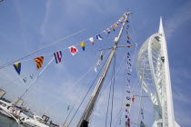 The Spinnaker Tower the tallest public viewing platforn in the UK at 170 metres on Gunwharf Quay with flag decorated yachts mast in the foreground