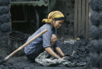 Woman making cakes of coal dust used as to fire kilns.