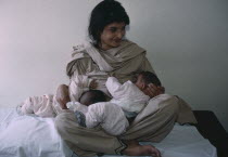 Pakistani woman breastfeeding her twins aged three months.