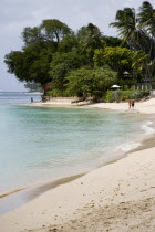 People walking along beach at Gibbes Bay past one of the exclusive houses