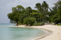 People walking along beach at Gibbes Bay past one of the exclusive houses