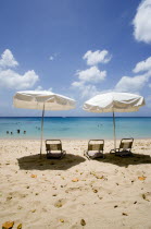 Sun shade umbrellas and chairs on Gibbes Beach with people swimming in the calm sea