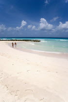 Couple walking towards sea defences on Rockley Beach also known as Accra Beach after the hotel there