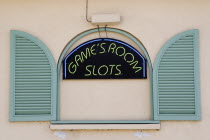 Gambling rooms neon sign in faked window promoting Slots in Holetown