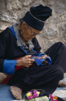 Hmong woman embroidering traditional textile.
