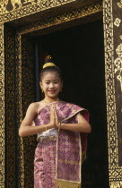 Young girl dressed for New Year festivities framed in doorway of temple.