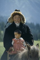 Kazakh grandfather and granddaughter on horse.