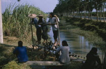 Women on treadmill lifting water for irrigation of crops.  This type of treadmill is rarely used today.