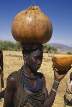 Karamong woman carrying water gourd on her head.