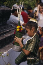 Young girl in traditional dress with flower offering during New Year celebrations. Buddhist