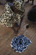 Woman using indigo coloured dye to tie dye fabric. Colored
