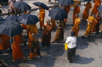 Line of monks holding umbrellas to protect themselves with water being thrown during New Year celebrations.