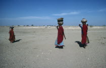 Women returning from village well carrying water on their heads.