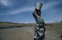 Woman carrying water from well on her head.