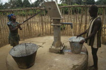 Young women using hand water pump.