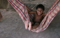 Panara indian child swinging in cloth hammock near Rio IririBrasil Kreen Akore