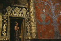 Young girl dressed for Lao New Year at Wat Xieng Thong with highly decorated exterior.Luang Phrabang Luang Prabang