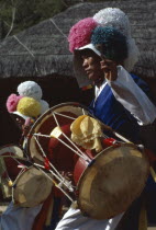 Farmers Dance.  Young man wearing paper flowered hat and playing drum.