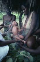 Azande women and child during ritual purification of new born baby in smoke.