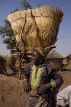 Girl standing below Grain store raised on stilts made from tree branches